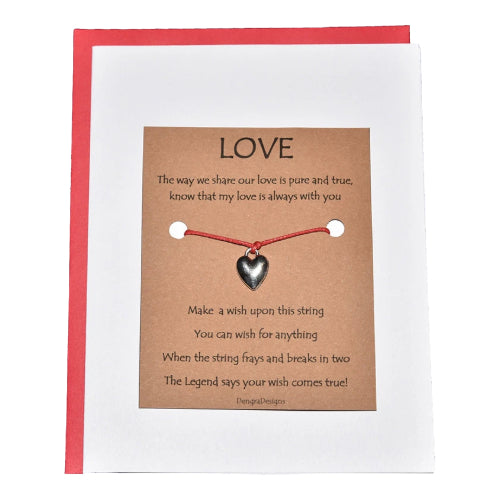 Card with a heart-shaped charm and red string on a brown card with text, against a white background.